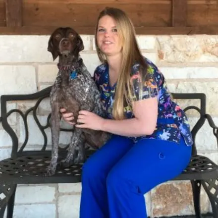 Amanda Armstrong holding a dog while sitting on a bench